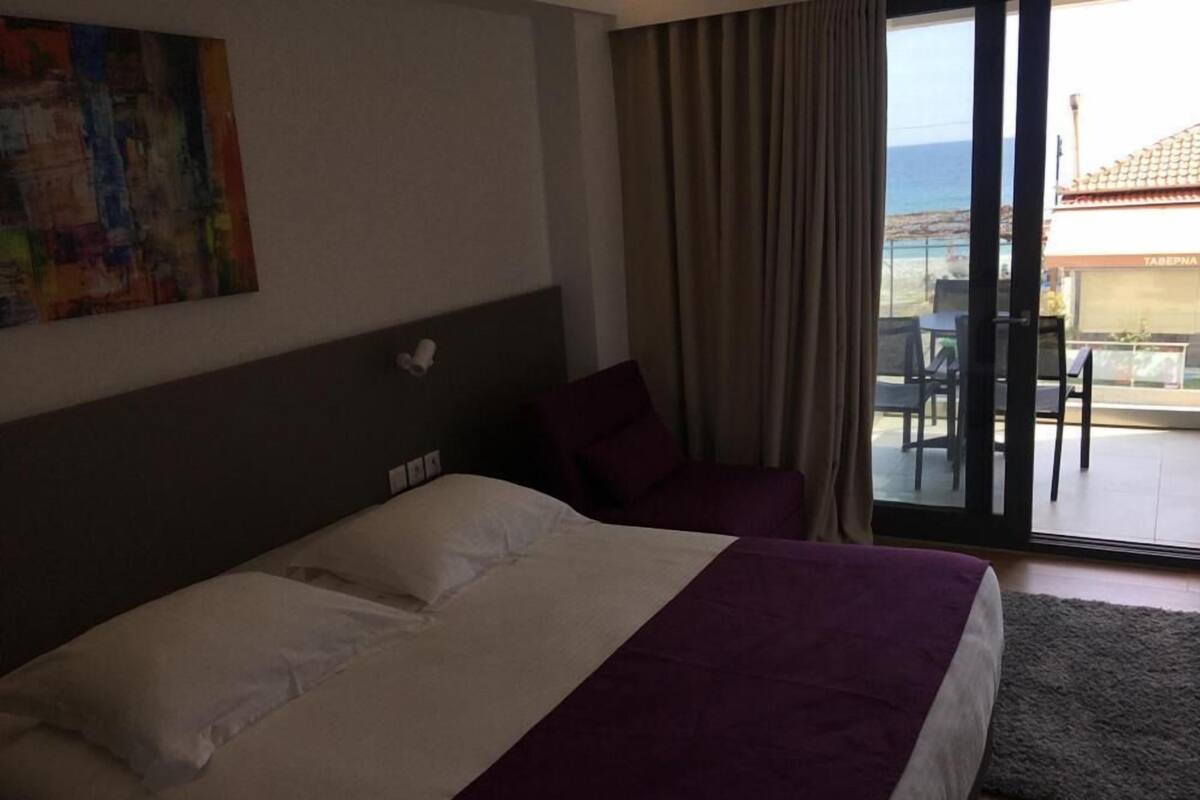 Una habitación de hotel con una cama, una silla, un cuadro y vistas al exterior.