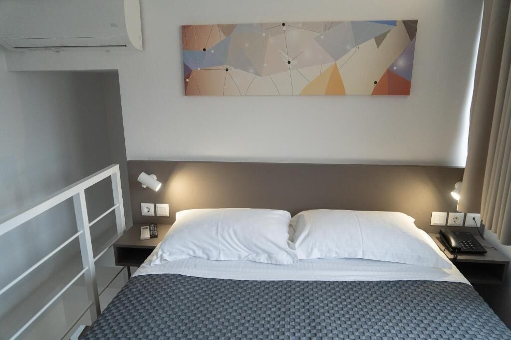 A hotel room with a bed, bedside tables, a phone, and a wall-mounted abstract painting.