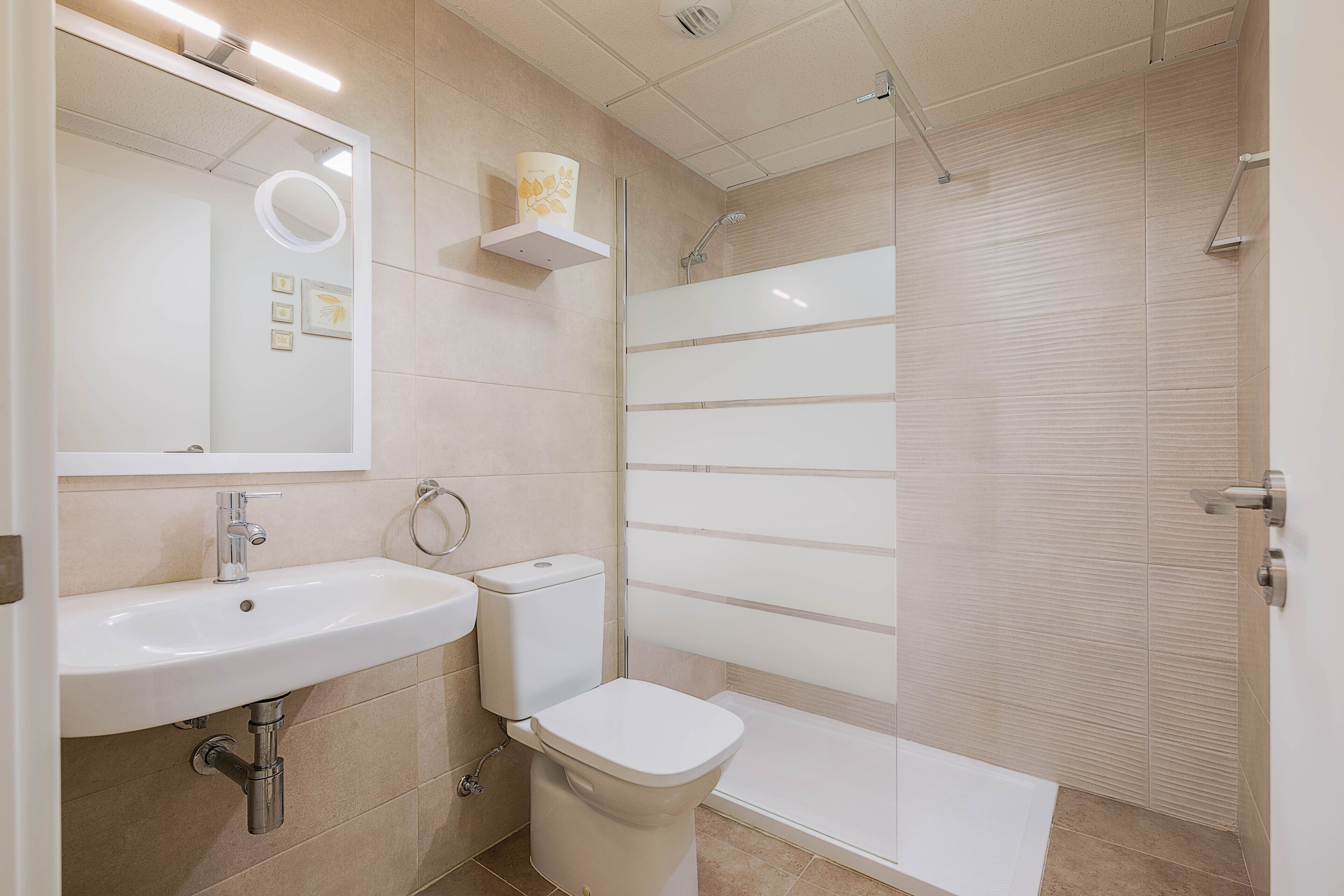 A modern bathroom with a sink, toilet, and shower area.