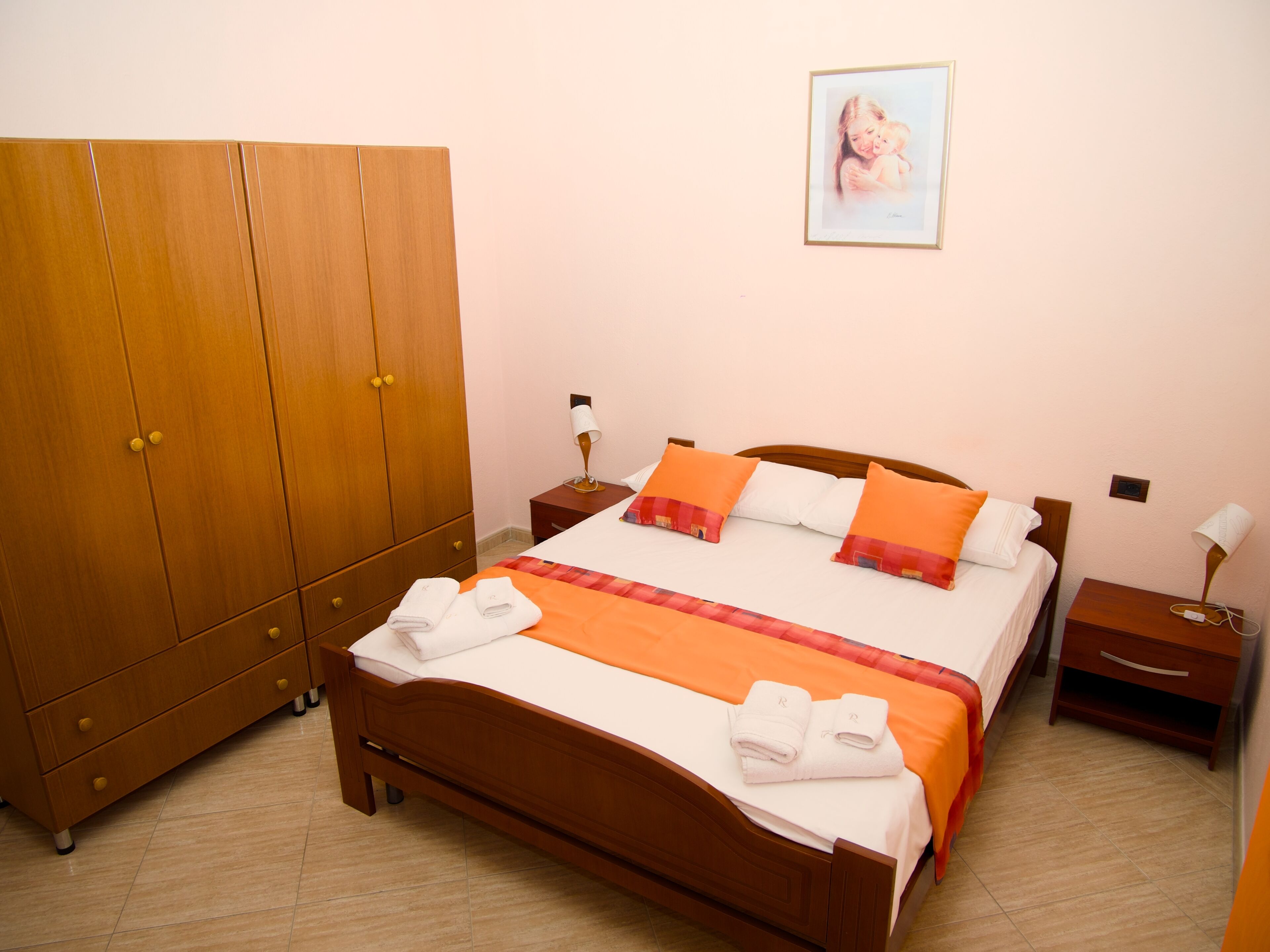Una camera da letto con un letto in legno, due comodini, un armadio e un quadro appeso al muro.