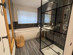Bathroom features a glass-enclosed shower, bathtub, and sink with mirror.