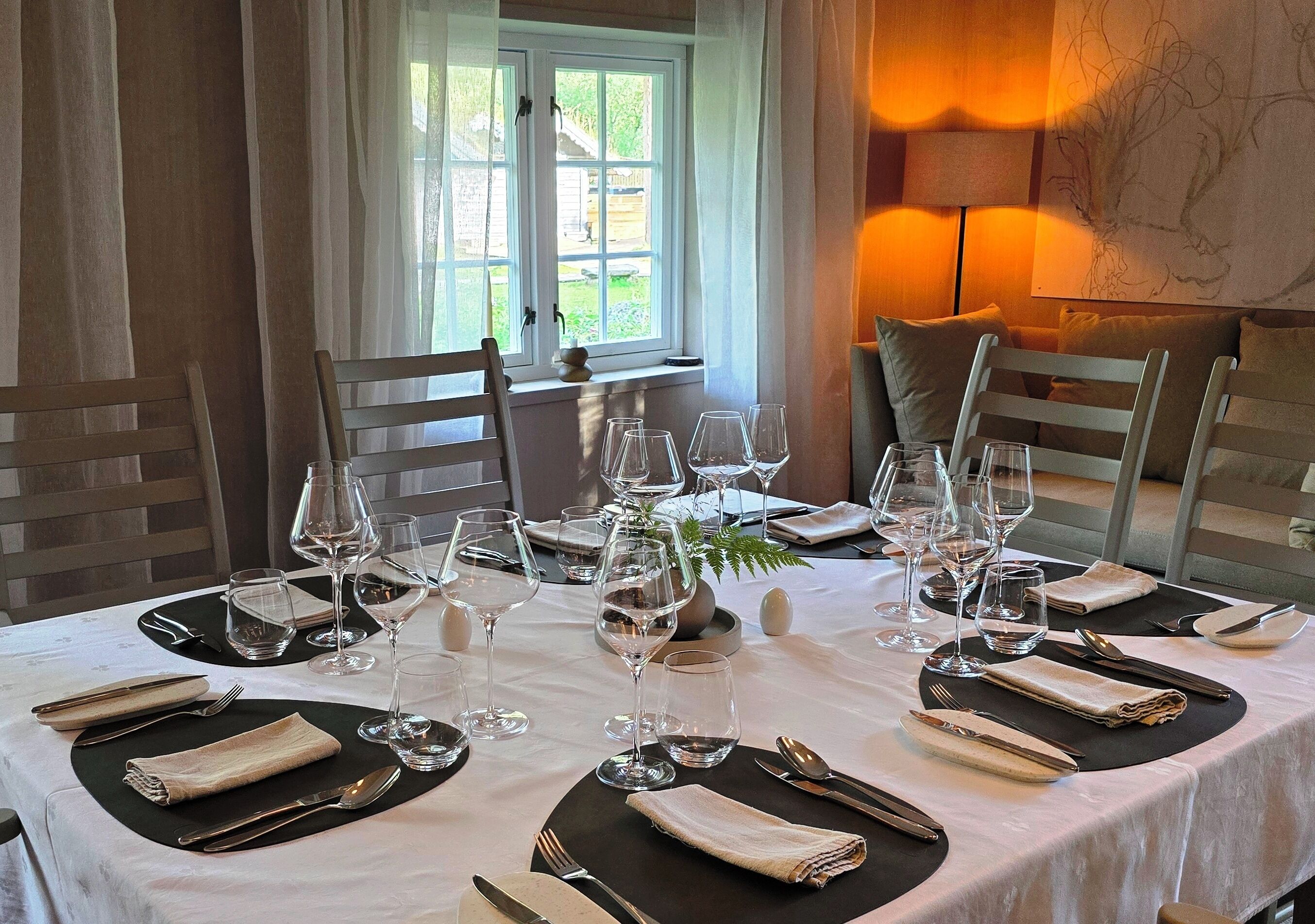 A dining table set for a meal with multiple wine glasses, cutlery, and napkins.