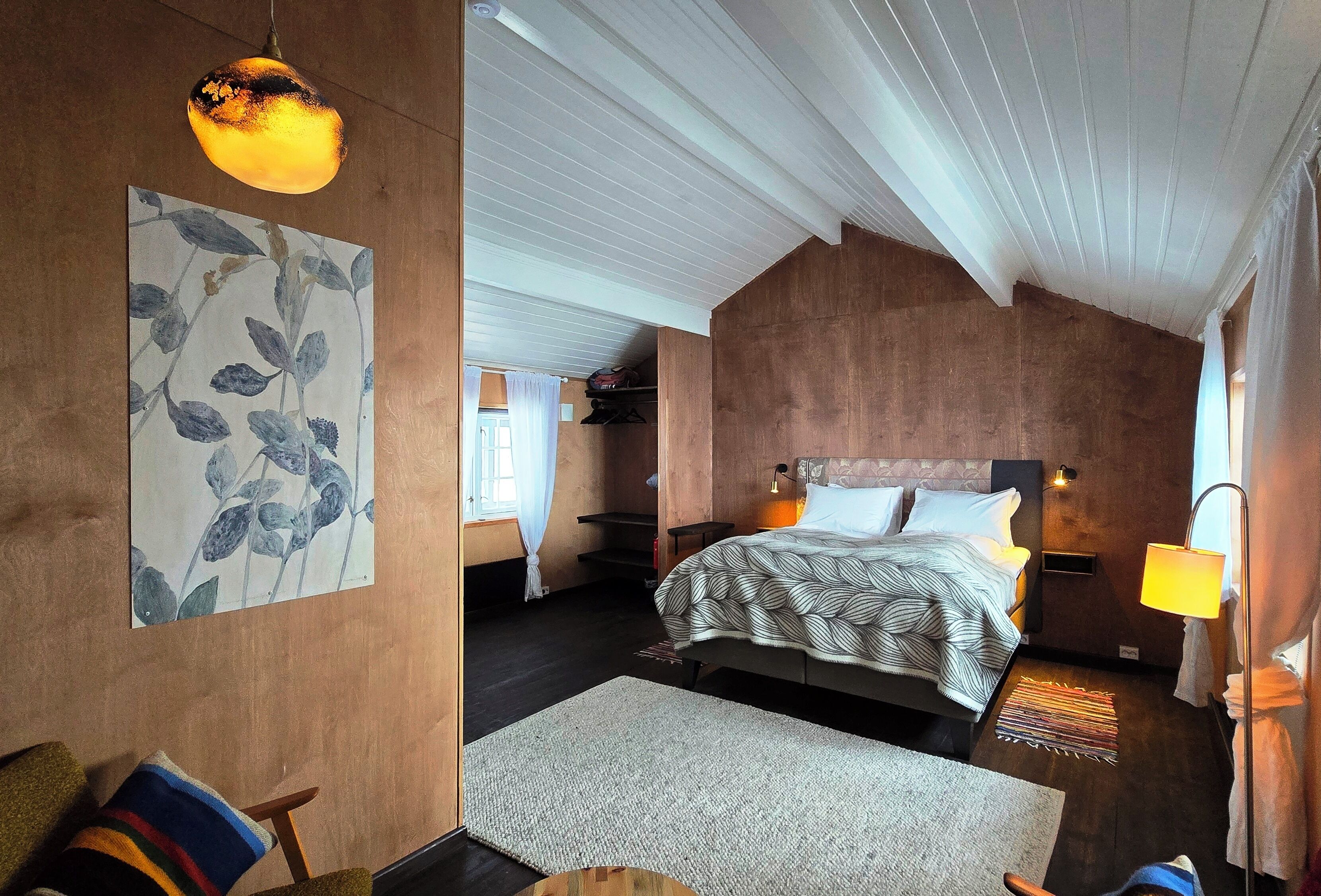 Ein Schlafzimmer mit Bett, Nachttisch, Lampe und Kunstwerk an der Wand.