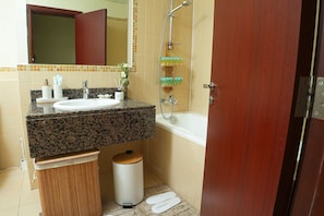 A bathroom with a sink, mirror, shower, and toilet.