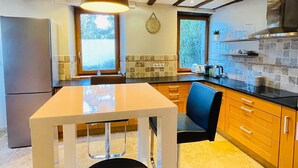A modern kitchen with a large island, wooden cabinets, and a window providing natural light. - Renovated 19th-century farmhouse, perfect for short or extended stays. (Saint-Julien-en-Genevois)