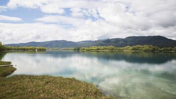 Un lago tranquilo con aguas cristalinas, rodeado de abundante vegetación y montañas a la distancia.