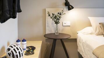 Una habitación de hotel con cama, mesita de noche y lámpara de pared.