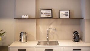 A modern kitchen with a stainless steel sink, a kettle, and a coffee machine. There are two framed pictures on the wall above the counter. - Double apartment (Banyoles)