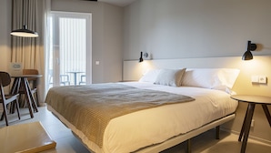 A hotel room with a large bed, a bedside table, a chair, and a small table with a lamp. - Double apartment (Banyoles)