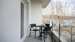 A balcony with a table and four chairs, overlooking a body of water and trees. - Double apartment (Banyoles)