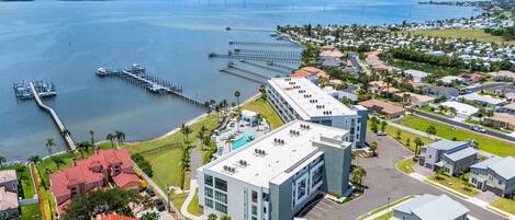 An aerial view of a coastal residential area with a marina, modern buildings, and a large body of water.