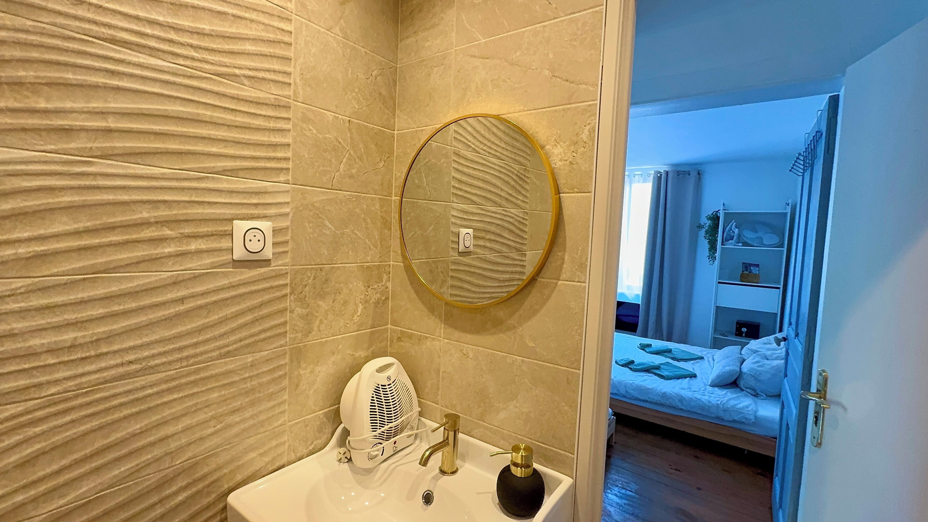 Une salle de bain avec un lavabo, un miroir et un porte-serviettes.