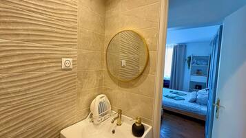 Une salle de bain avec un lavabo, un miroir et un porte-serviettes.