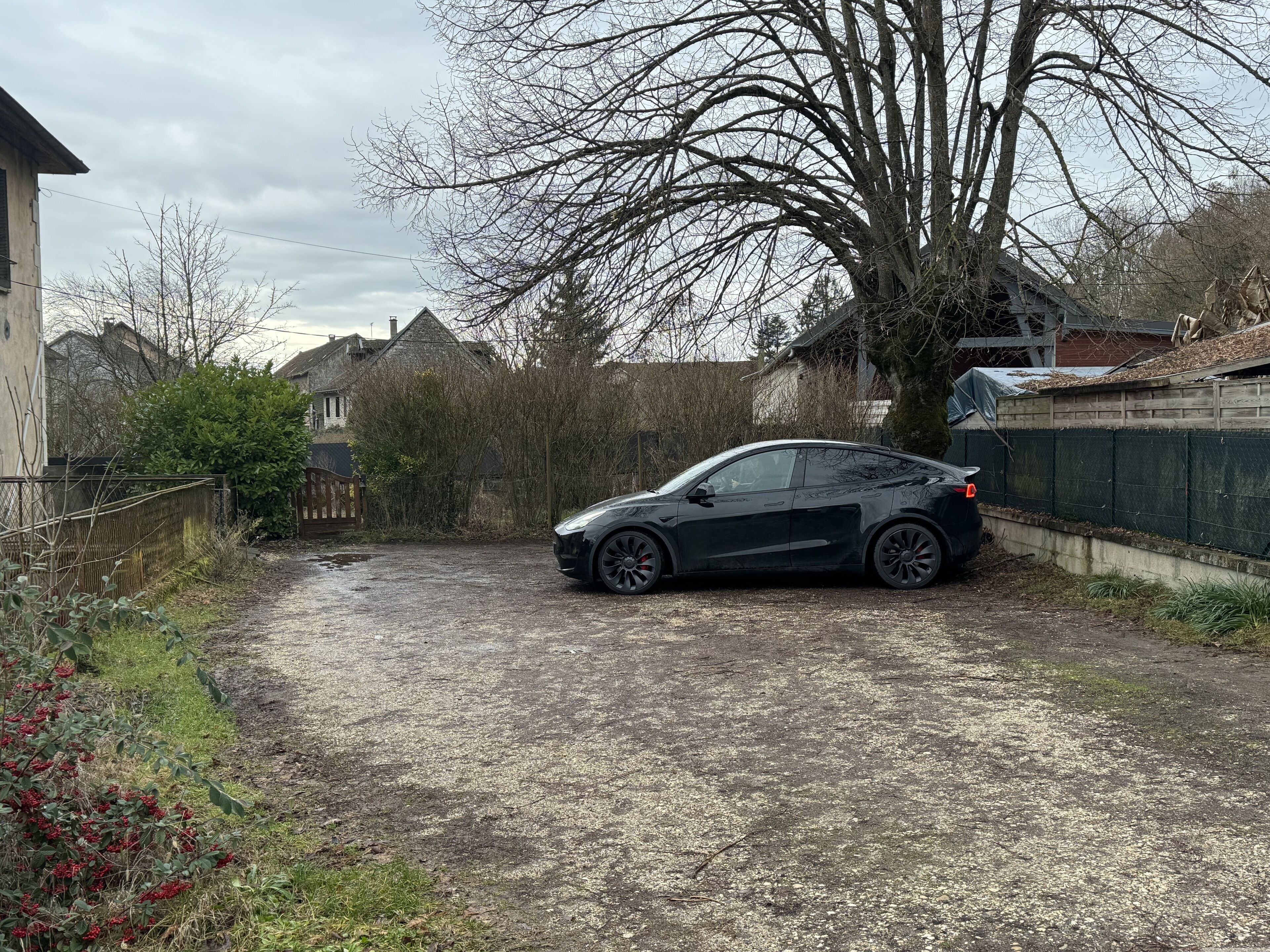 Un'auto nera parcheggiata in un vialetto, con una casa sullo sfondo.