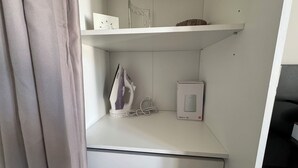 Siististi järjestetty hylly, jossa on valkoinen silitysrauta, laatikko, jossa lukee ”Flybox 4G+”, ja koriste-esine.