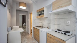 A modern kitchen with a sink, stove, and wooden cabinets. - Sun City Apartments by Estia (Agios Nikolaos)