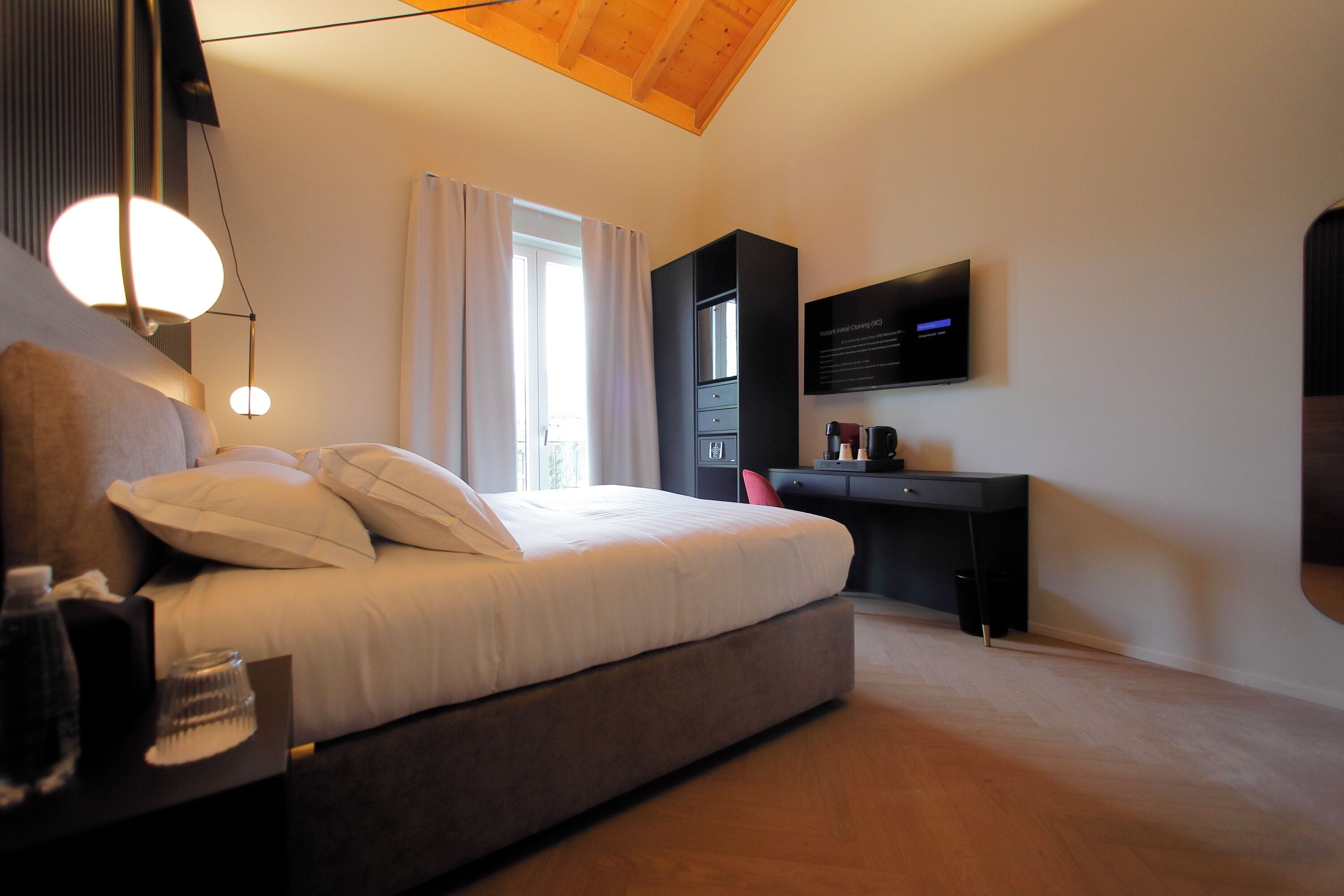 Un dormitorio moderno con cama, mesita de noche, escritorio y televisor de pantalla plana montado en la pared.
