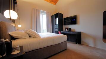 Un dormitorio moderno con cama, mesita de noche, escritorio y televisor de pantalla plana montado en la pared.