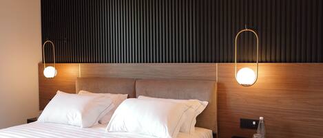 A neatly made bed with white linens, a wooden headboard, and two bedside lamps.