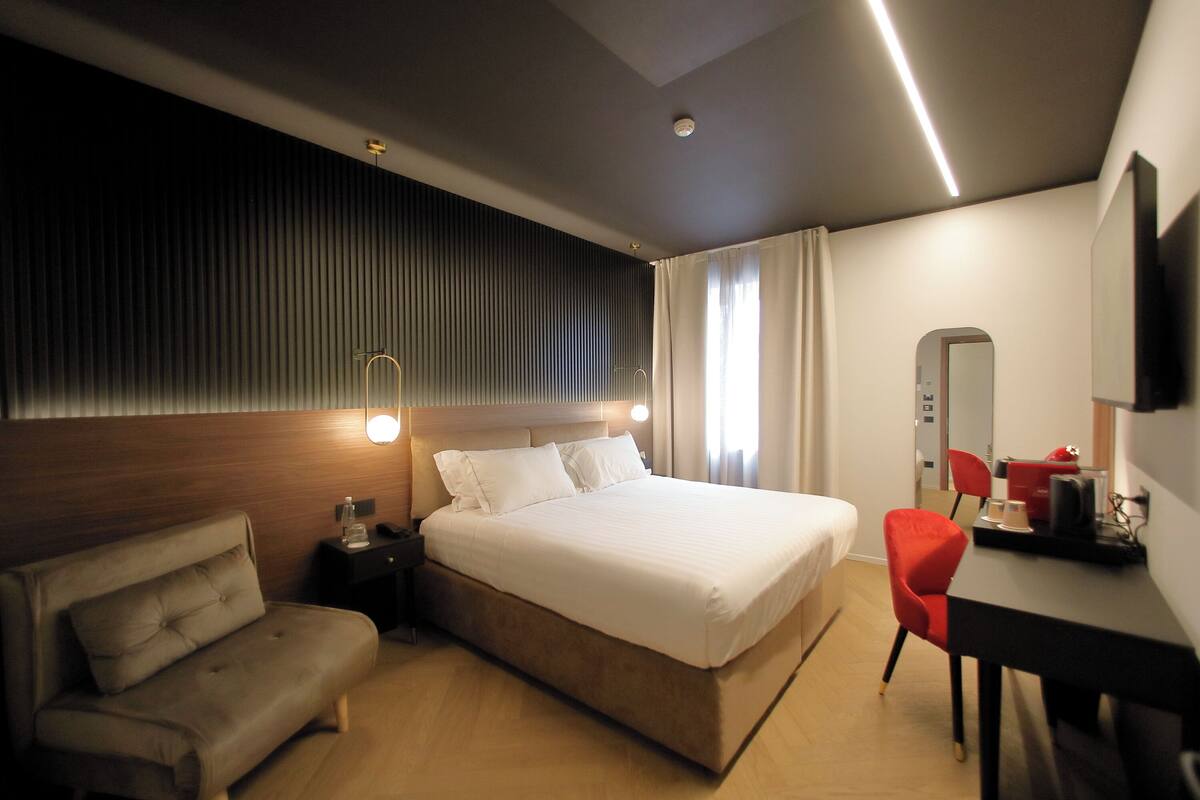 Une chambre d’hôtel moderne avec un grand lit, un canapé, un bureau et un miroir.