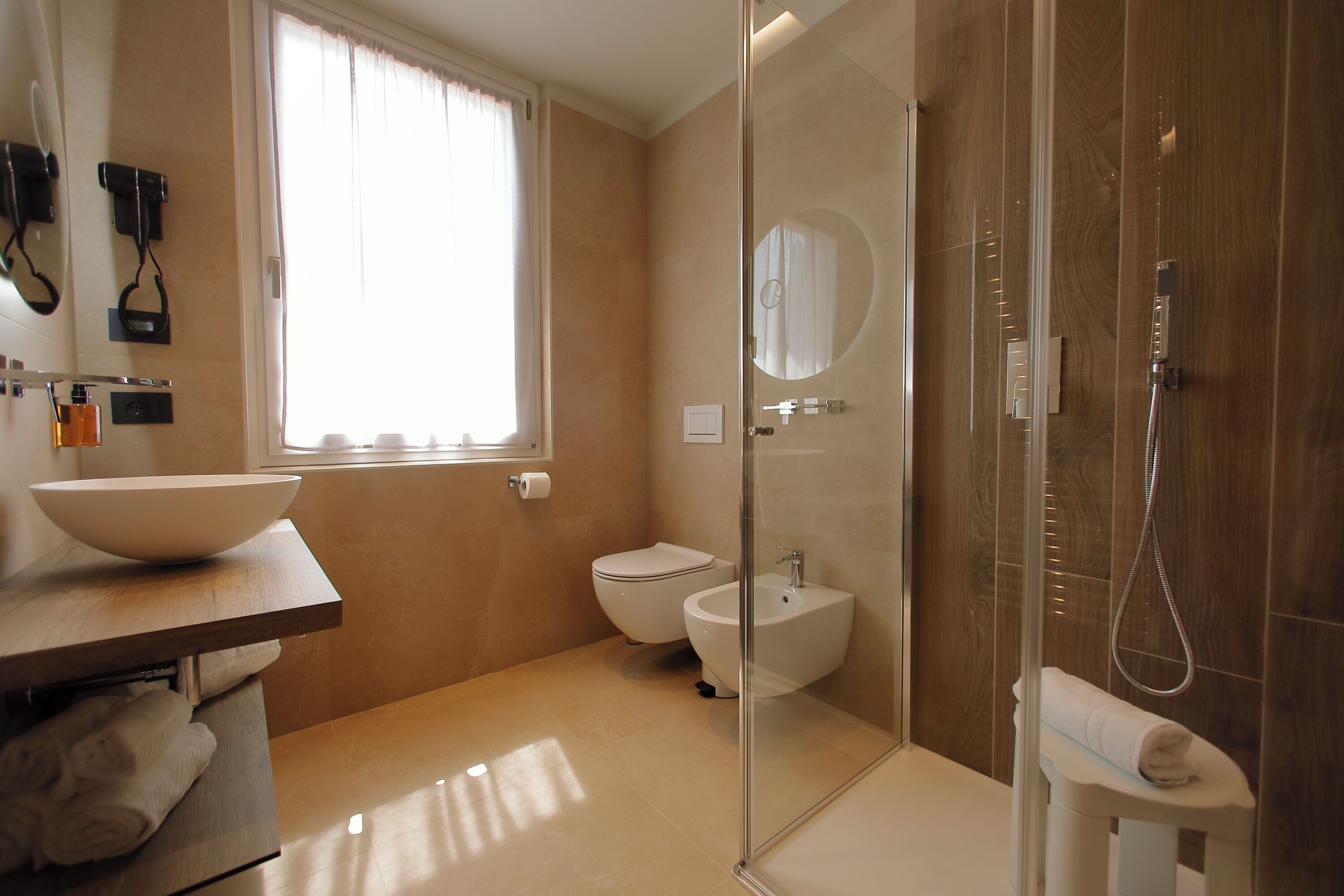 Un baño moderno con un lavamanos grande, inodoro, bidé y ducha con mampara de vidrio.