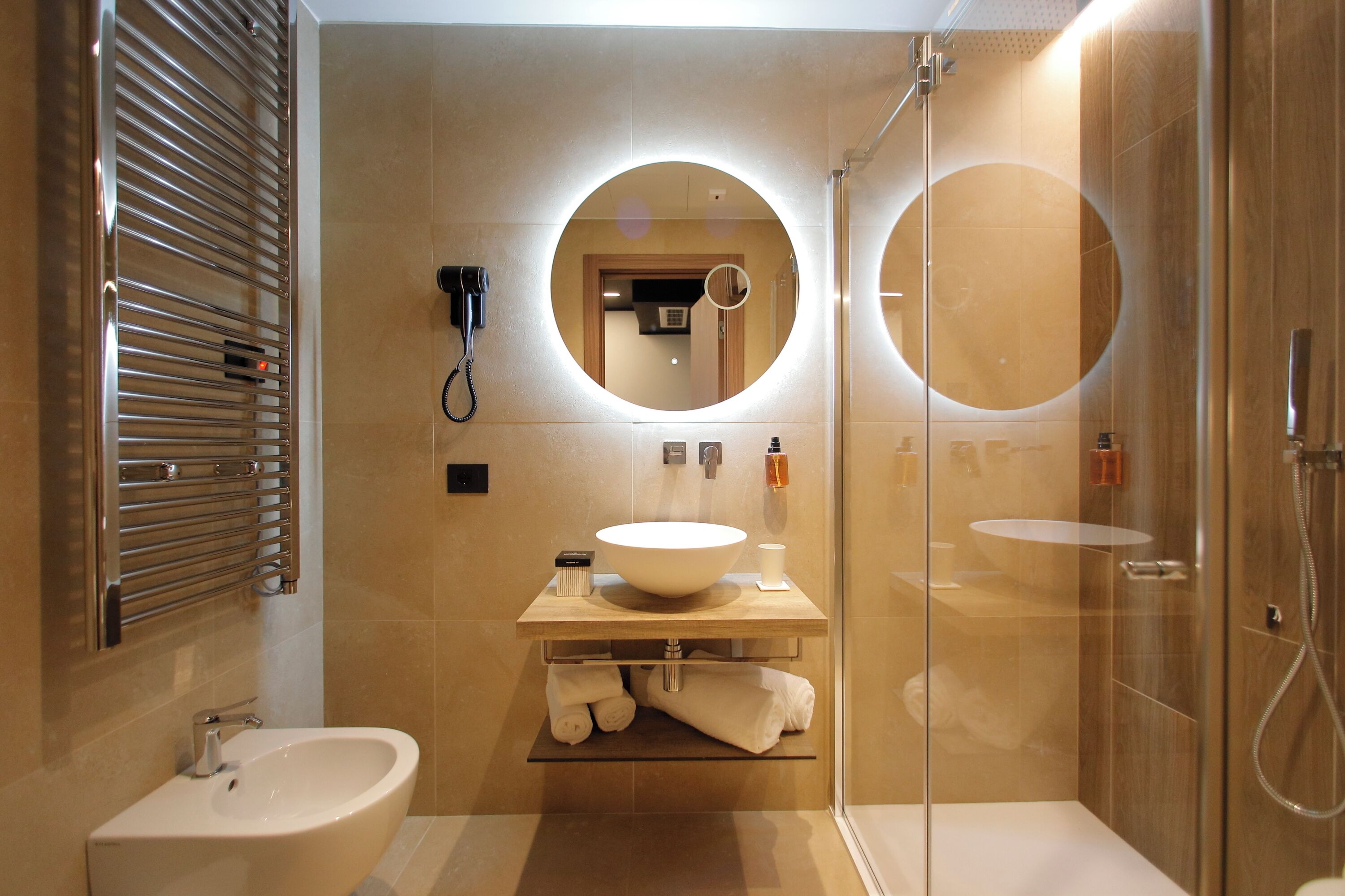 Une salle de bain moderne avec un grand lavabo, un miroir, une douche à parois de verre et un porte-serviettes.