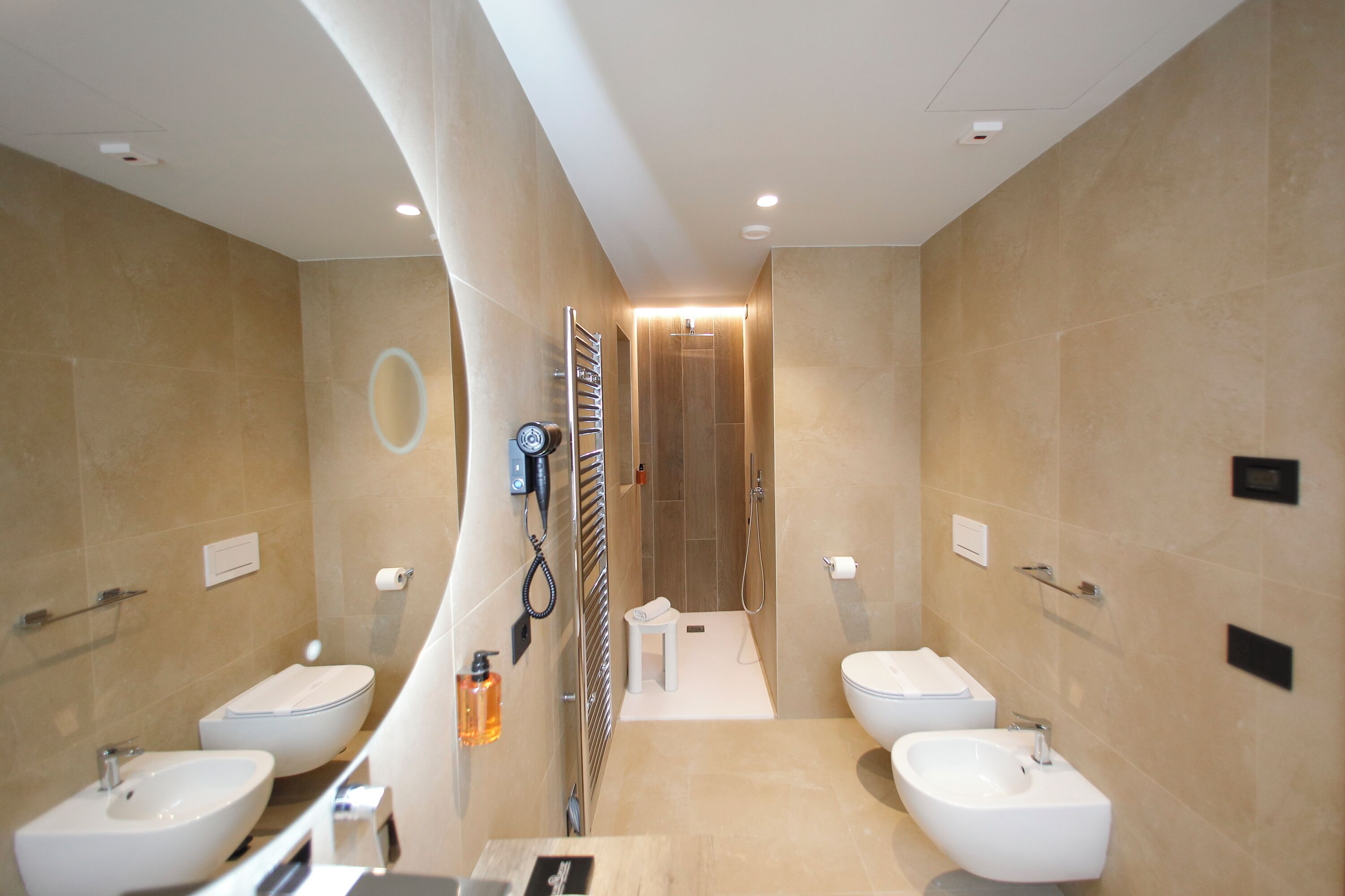 Un baño moderno con dos lavamanos, un secador de pelo y un perchero para toallas.