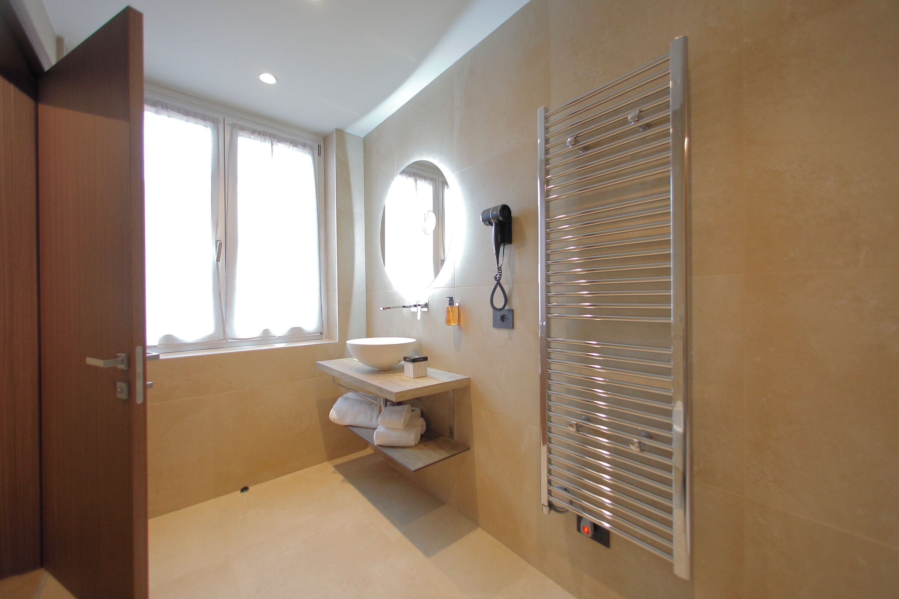 A bathroom with a vanity, a mirror, a towel rack, and a towel warmer.