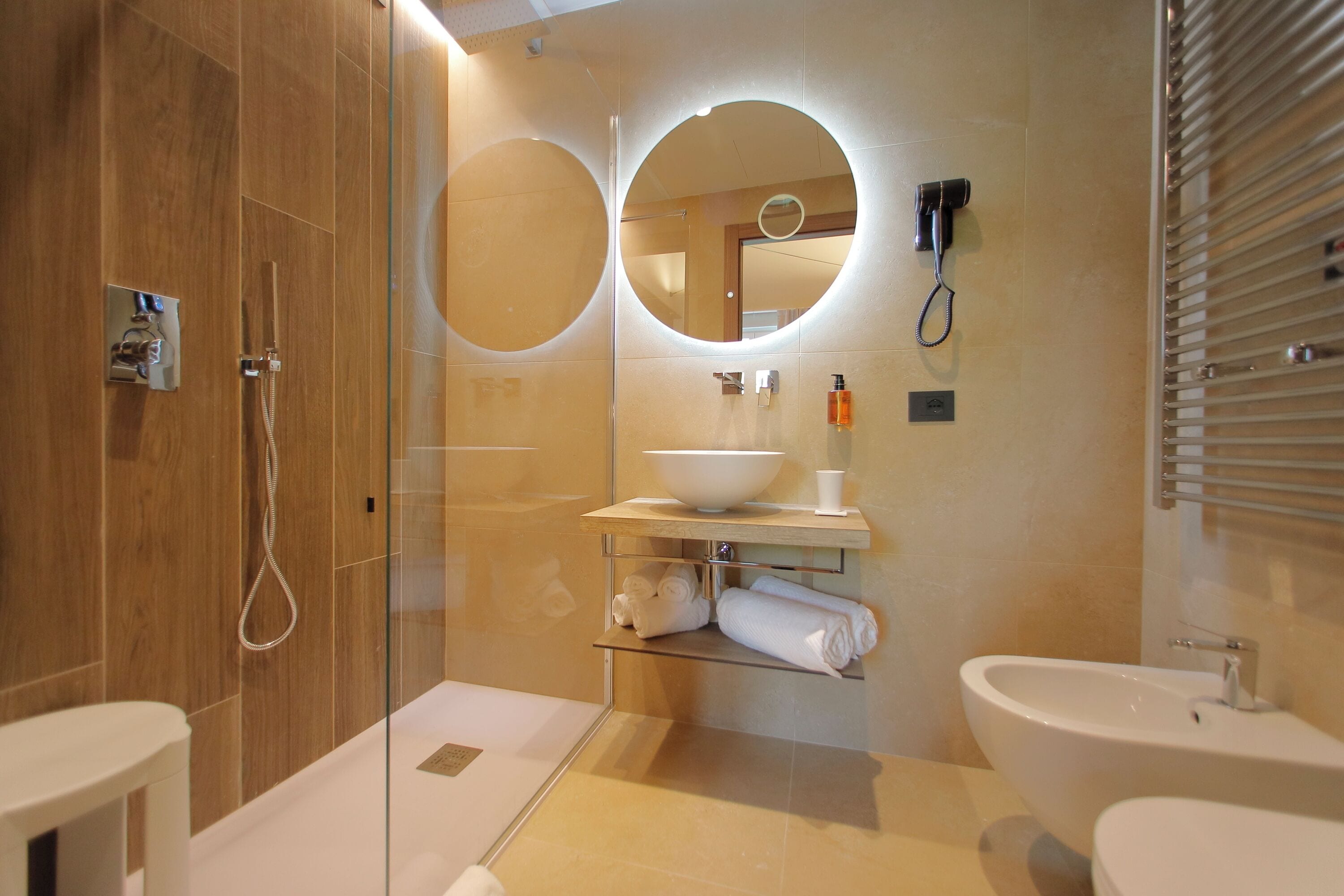 Ein modernes Badezimmer mit einer einteiligen Duschkabine, einem runden Spiegel, einem Waschbecken und einer Toilette.