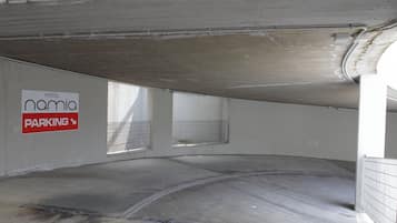 Un área de estacionamiento con un letrero que dice 'Hotel Namia' y una rampa metálica que conduce a un nivel superior.