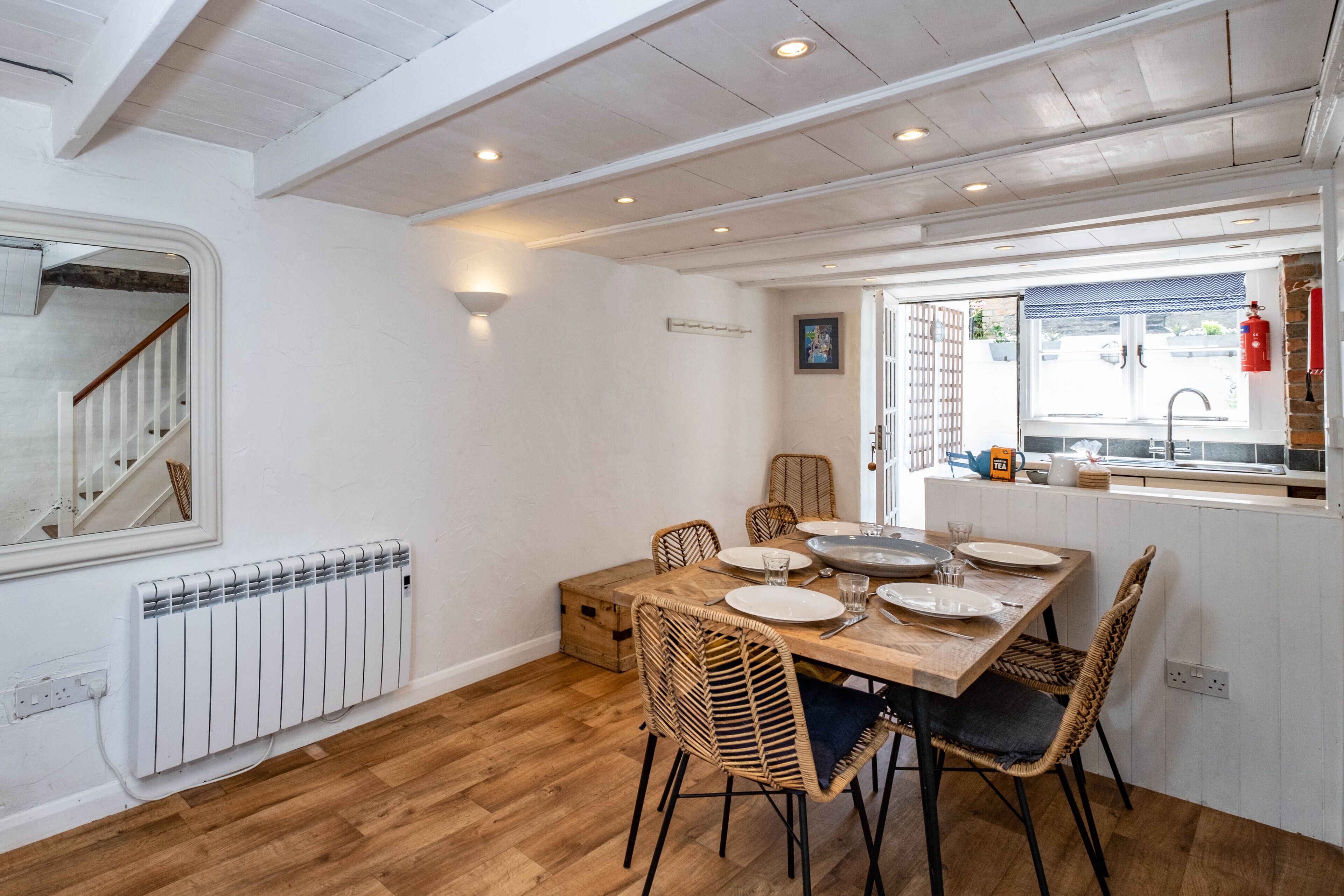 Een eethoek met een houten tafel, rieten stoelen en een witte radiator.