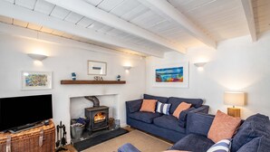A cozy living room with a fireplace, a sofa set, a television, and artwork on the walls. - Sea Horses (Port Isaac)