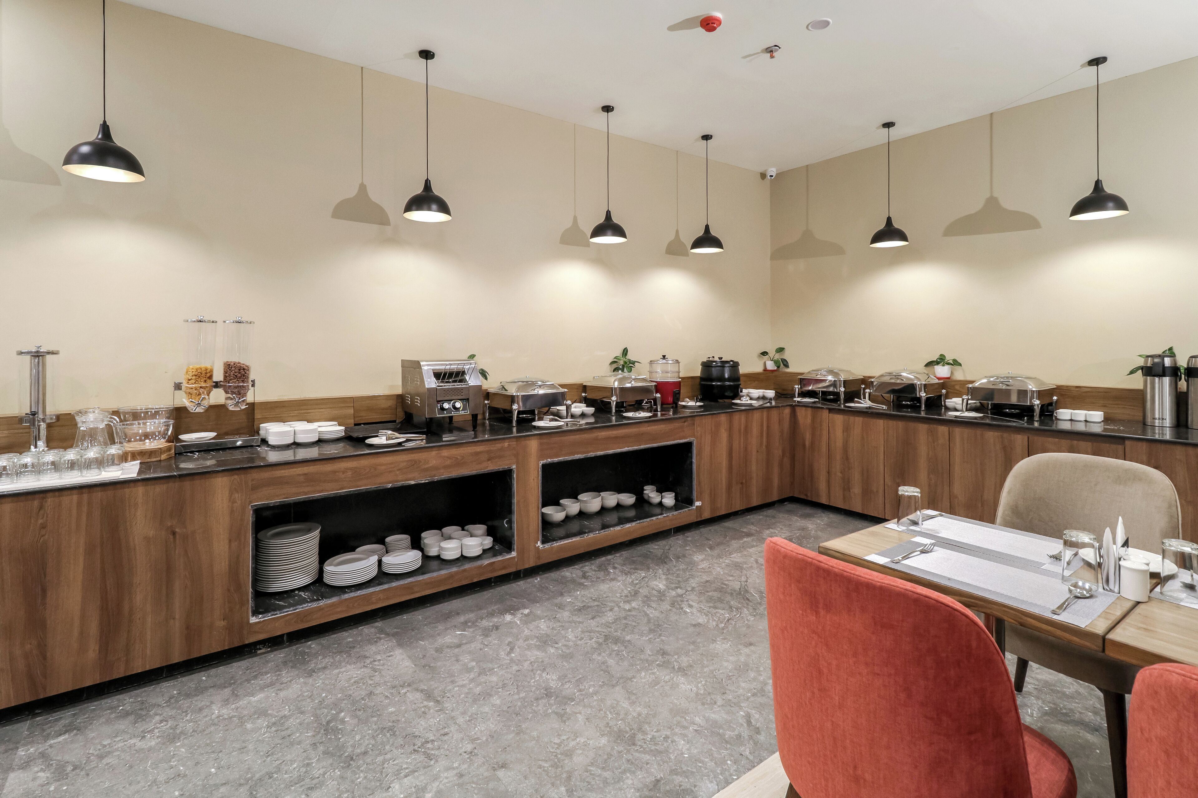 A modern breakfast bar with multiple serving stations, a wooden counter, and a seating area with a table and chairs.