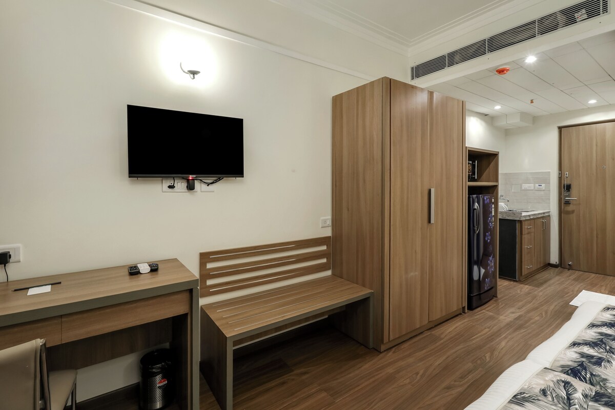 Una habitación de hotel moderna con un escritorio de madera, un banco y un armario.