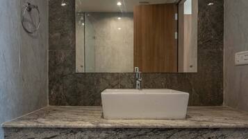A bathroom with a white sink, marble countertop, and a large mirror.
