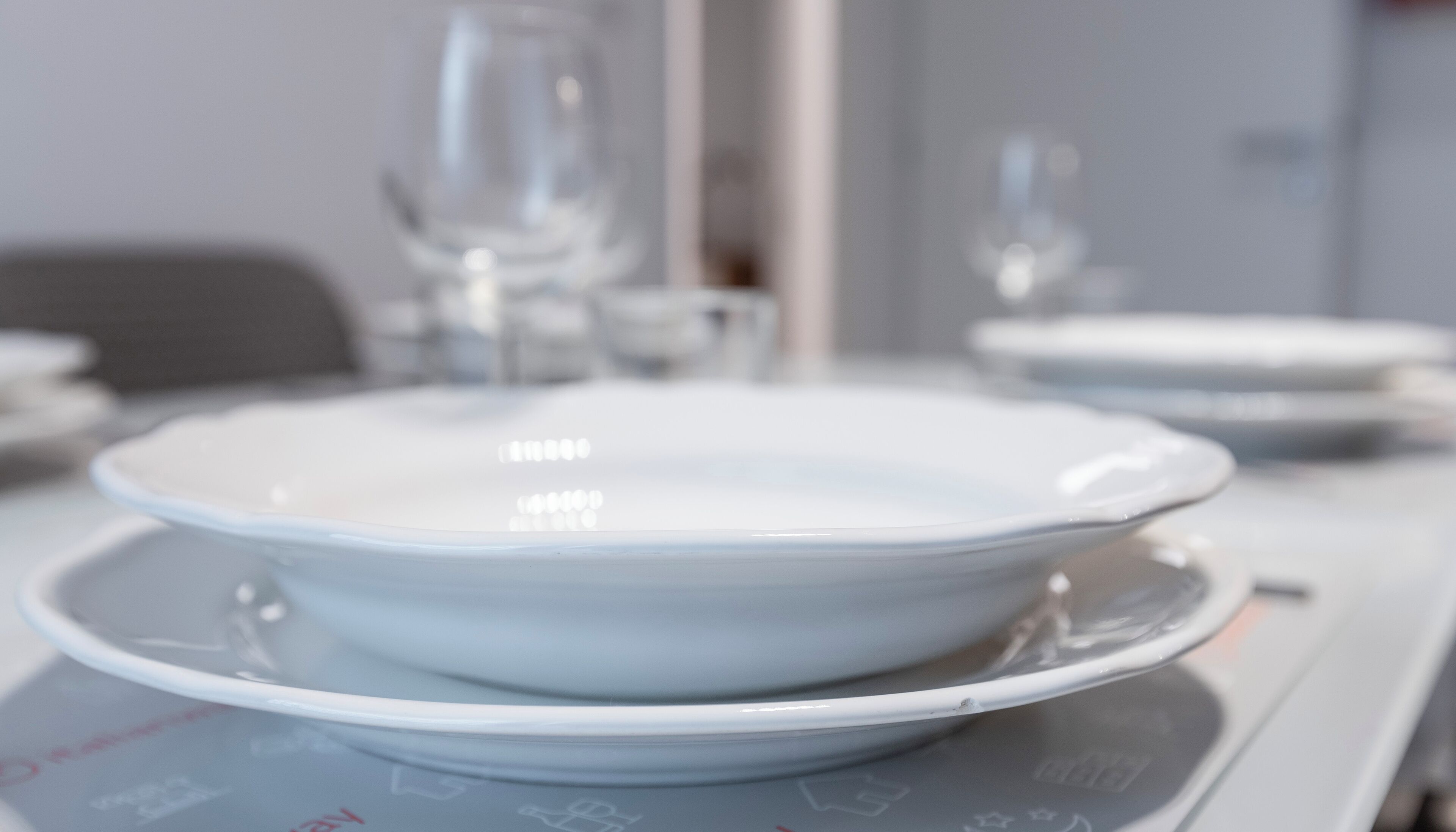 A dining table with white plates and clear glassware.