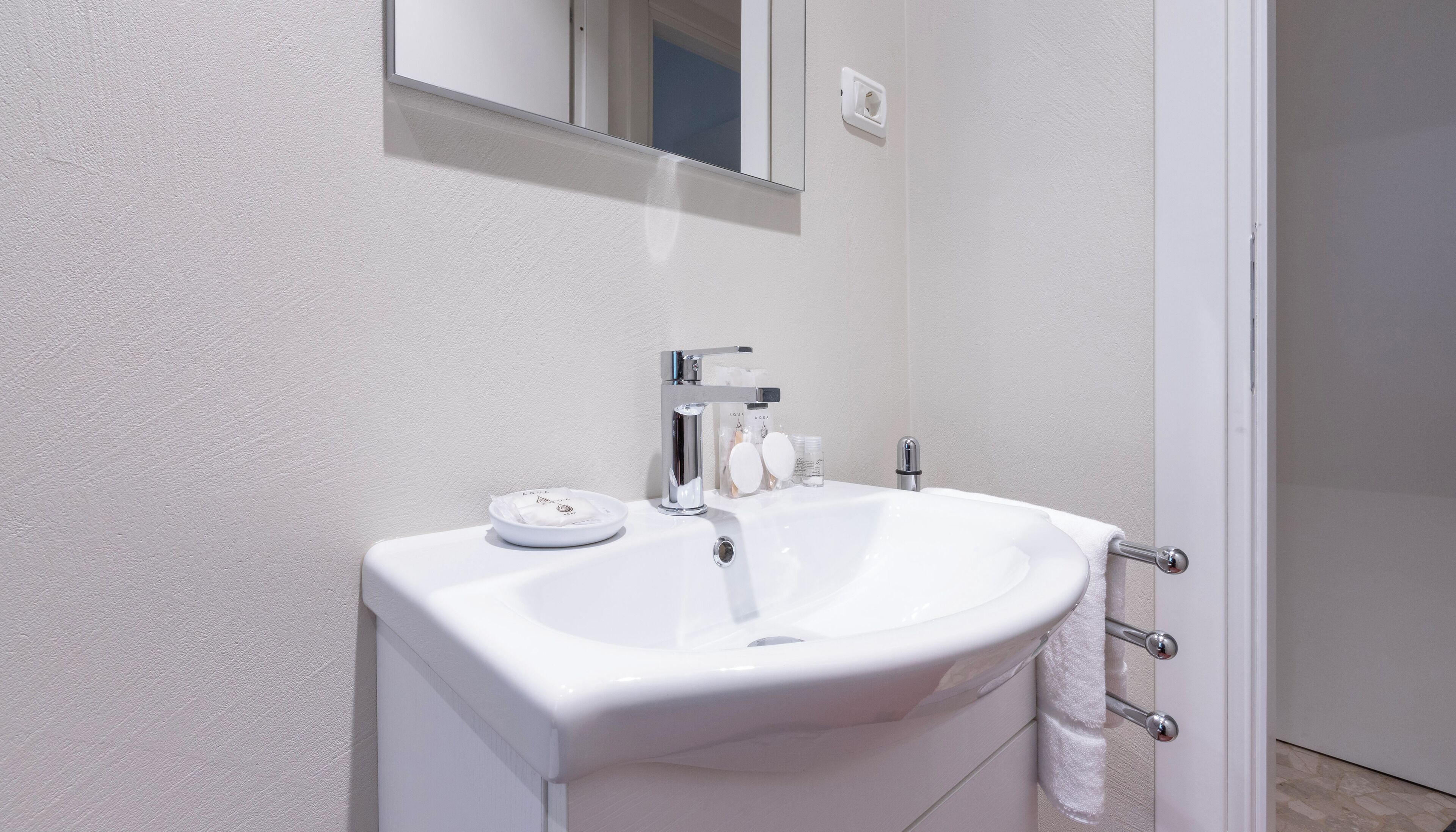 Ein Badezimmer mit Waschbecken, Spiegel und Handtuchhalter.