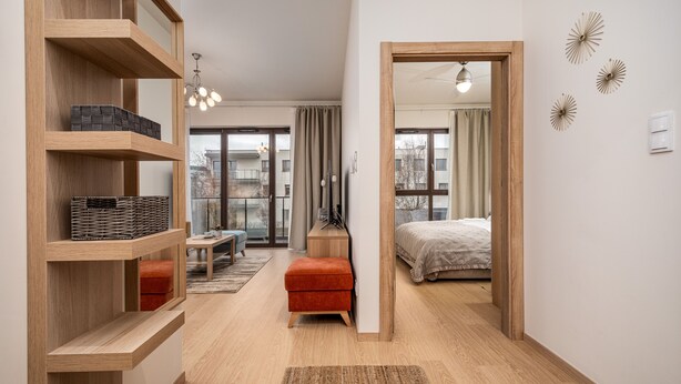 Une chambre à coucher moderne avec un lit, une armoire en bois, une petite table et un banc rouge.