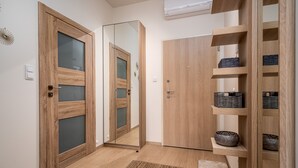 Un couloir avec des portes en bois, un miroir et des étagères où sont posés des paniers.