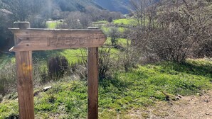 Un panneau indicateur en bois, situé dans une région montagneuse, sous un ciel dégagé.