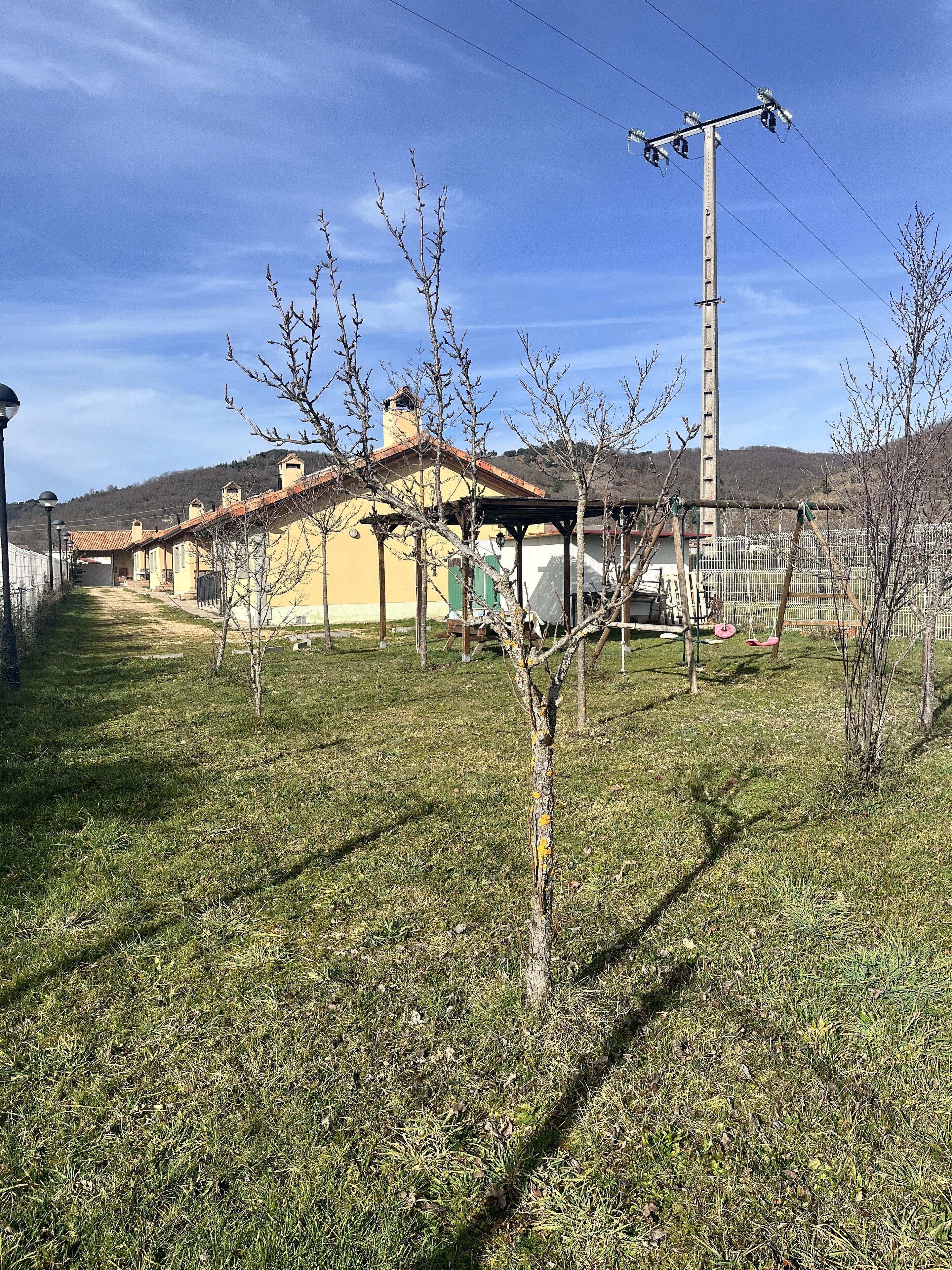 Un quartier résidentiel avec des maisons, une ligne électrique et un champ d’herbe.