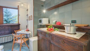 A kitchen with a wooden countertop, a microwave, a sink, and a window with a view of trees. - Fiori di Miele few Step From Skiing (Bardonecchia)