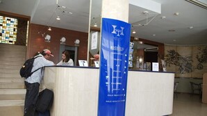 A reception desk with a blue sign listing amenities like a restaurant, bar, and pool. - Terramar (Calella)