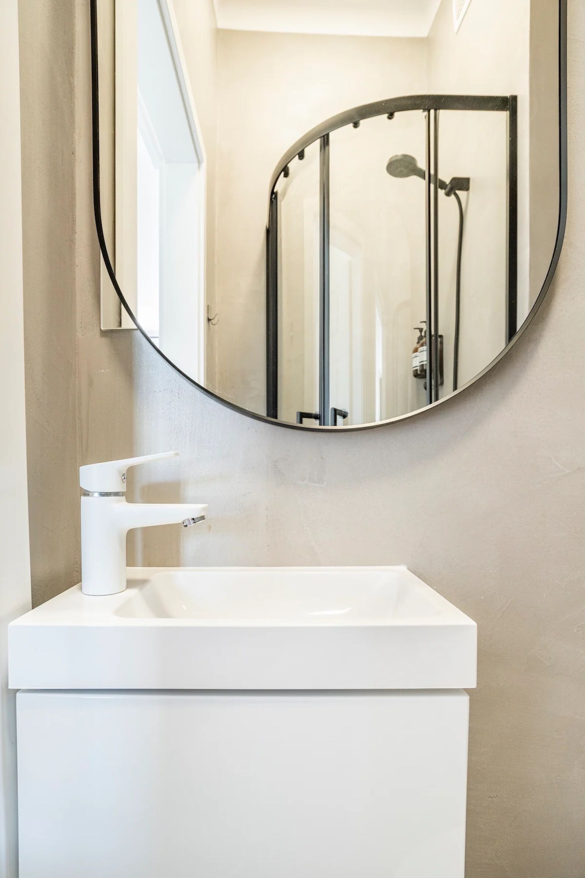 A bathroom with a white sink, a mirror, and a shower enclosure.