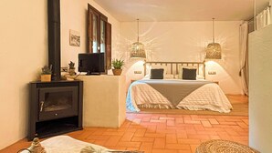 Une chambre confortable avec une cheminée, deux lits et des lampes suspendues.