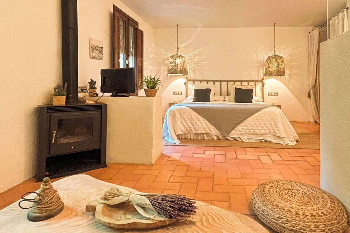 Een knus slaapkamer met een open haard, twee bedden en hanglampen.