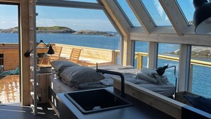 Una cabaña acogedora con tragaluces, una pequeña cocina con pileta y estufa, y vista al agua.