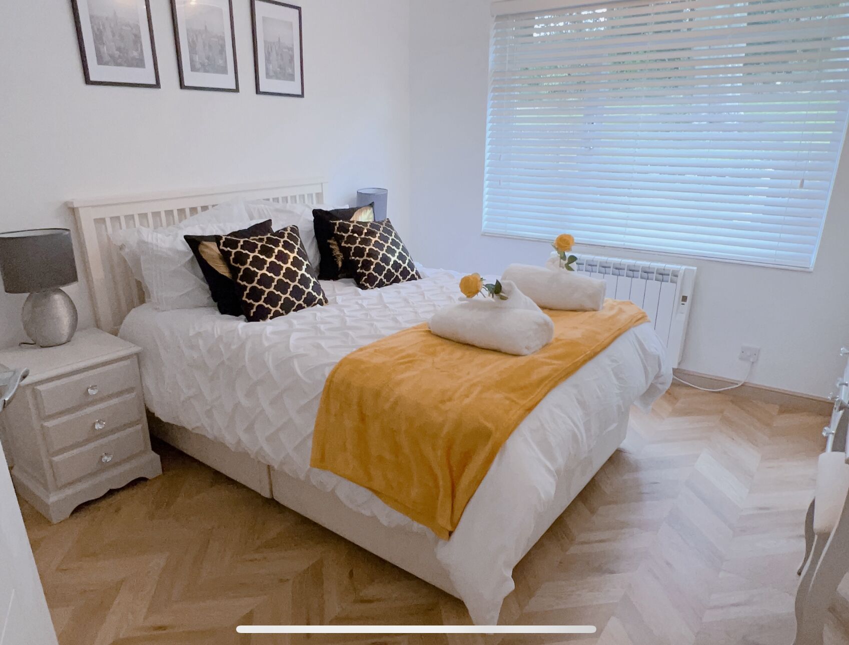 Une chambre à coucher bien rangée, avec un lit, des tables de chevet, une lampe et un radiateur.