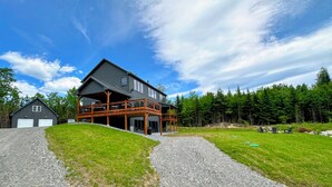 Une maison à deux étages dotée d’une grande terrasse et d’un espace extérieur couvert.