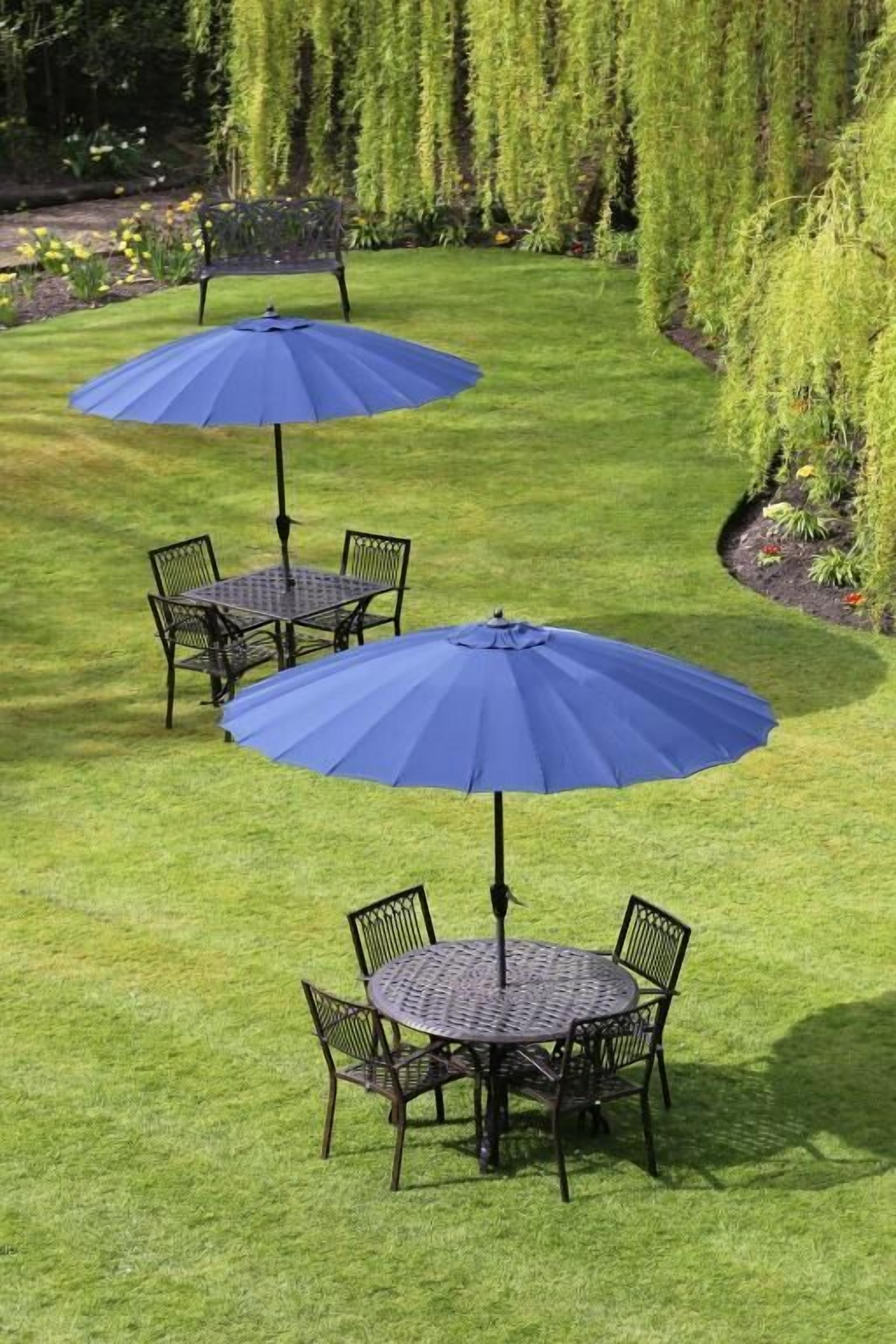 A patio area with two round tables and chairs, each with a blue umbrella.